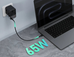 Laptop plugged into a power adapter with '65W' displayed on a gray surface.
