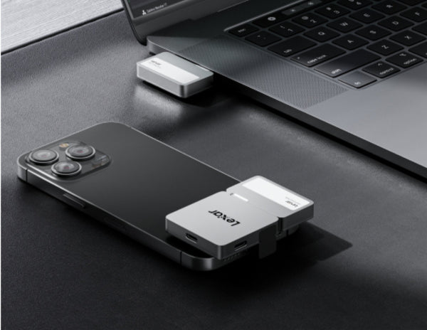 Phone with a USB-C adapter connected to a laptop on a dark surface