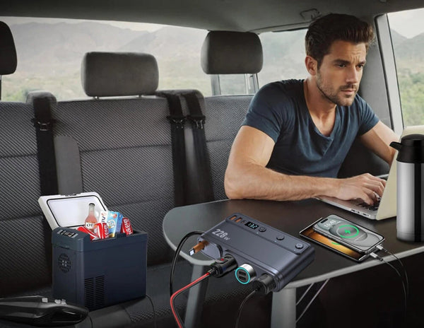 Man using a portable power station in the back of a car with various devices plugged in.