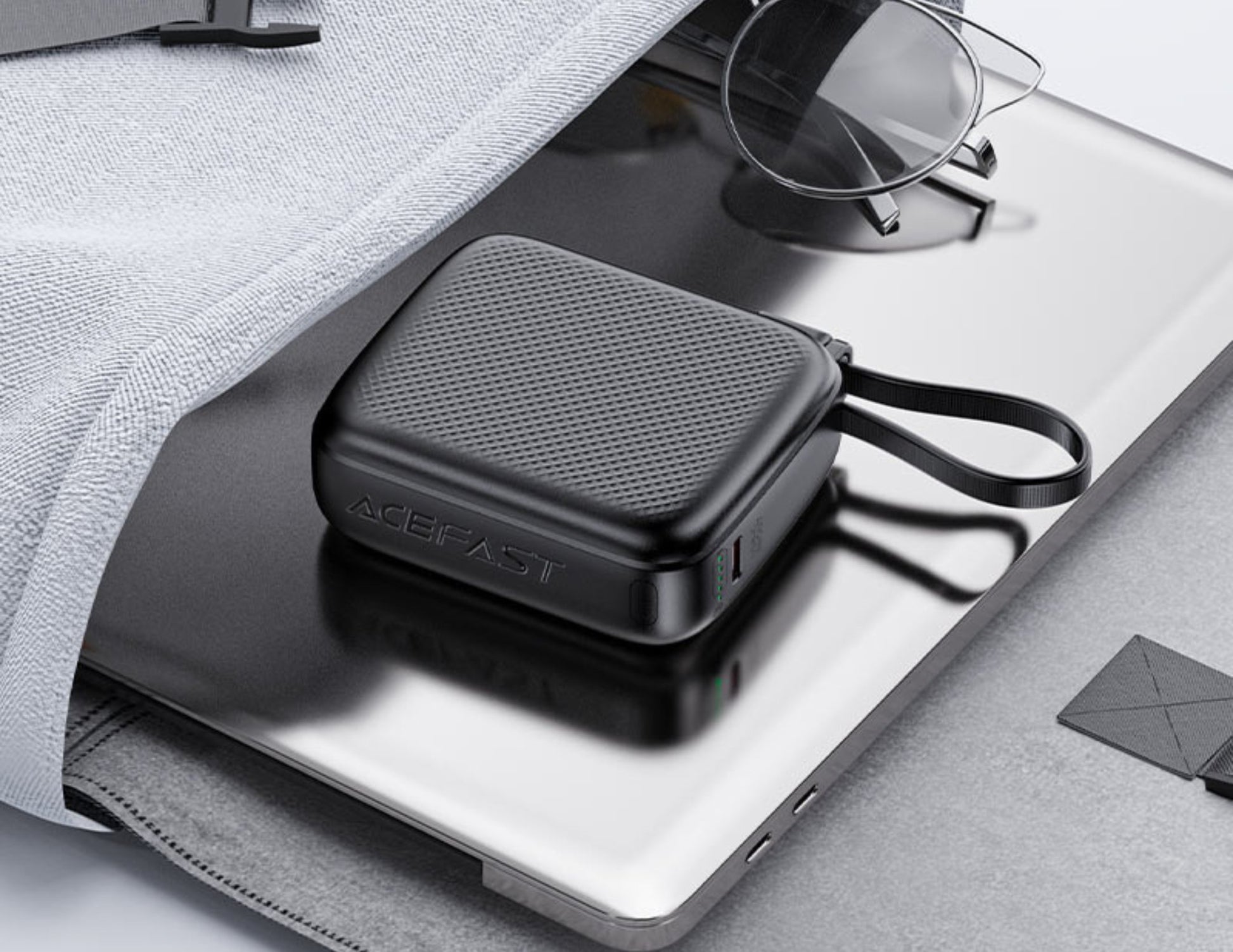 Acefast M15 10000mAh Power Bank on a gray surface with sunglasses and a gray bag.