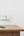 Phone charging on a wooden table with a white wall and brass door handle in the background