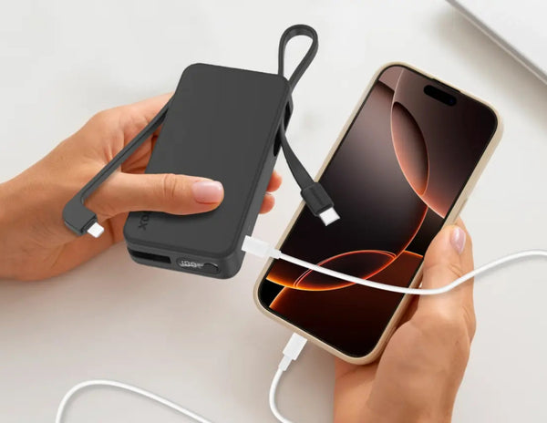 Person using a black portable charger to power a smartphone on a light gray background