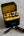 Black and yellow TakTik battery case with batteries on a concrete surface