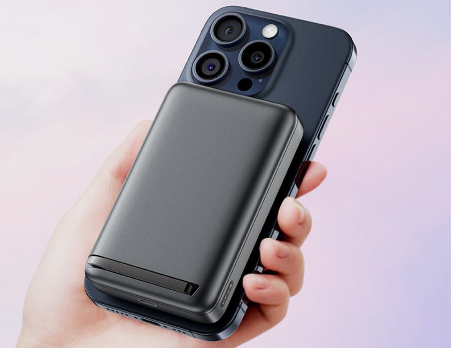 Hand holding a smartphone with a black case against a light pink background