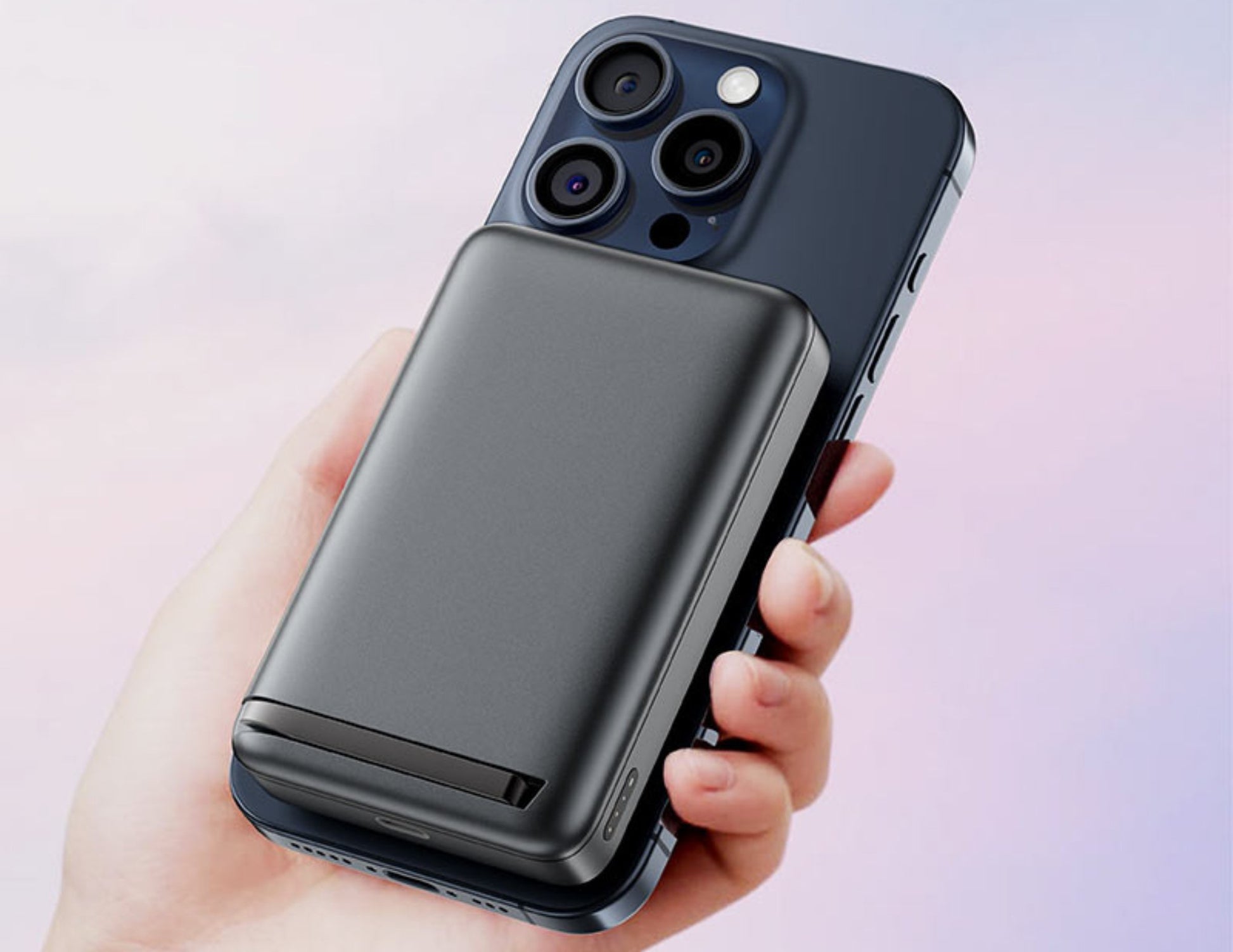 Hand holding a smartphone with a black case against a light pink background