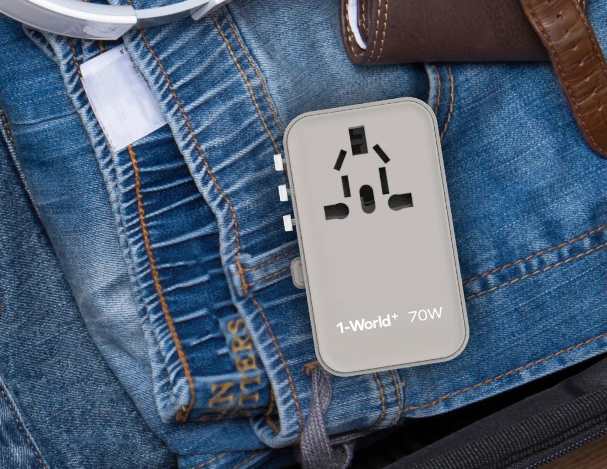 Gray Momax 1‑World+ 70W GaN 3‑Port Travel Adapter with Retractable USB‑C Cable – UA18 on a blue denim surface