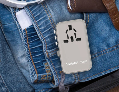 Gray Momax 1‑World+ 70W GaN 3‑Port Travel Adapter with Retractable USB‑C Cable – UA18 on a blue denim surface