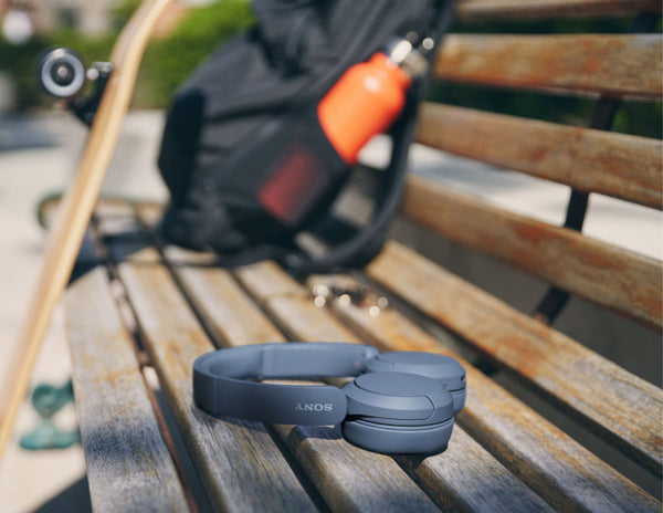 Blue Sony headphones on a wooden bench with a blurred background
