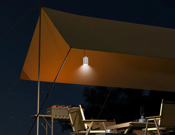 Camping setup with a canopy and light fixture against a night sky.