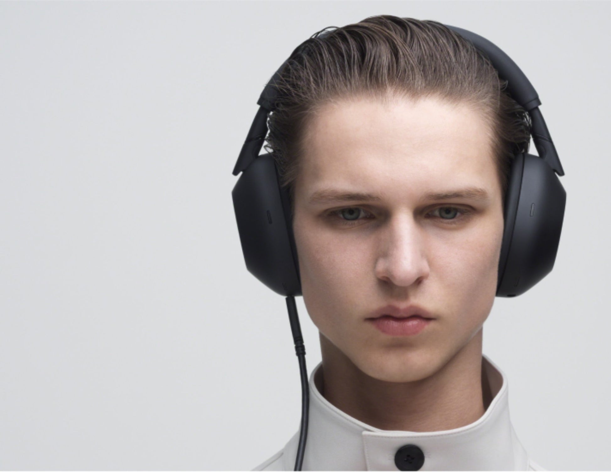 Person wearing large Sony WH-1000XM6 Wireless Noise Canceling Headphones – Black on a light gray background