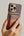Hand holding a phone with a Pitaka MagSafe Woven Wallet – Magsafe Compatible MWW240 against a neutral background