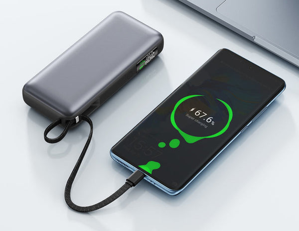 Phone being charged by a power bank on a white surface