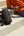 Person sitting on steps with a skateboard and Tomtoc GameOn-G49 Nintendo Switch 2 Sling Bag – Black (G49S1D1), wearing an orange shirt and blue jeans.
