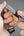 Close-up of hands adjusting a gray and black woven bracelet on a plain background.