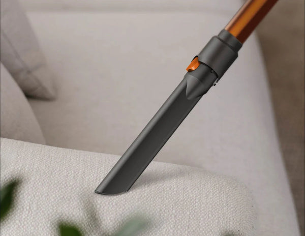 Vacuum cleaner attachment being used on a sofa.