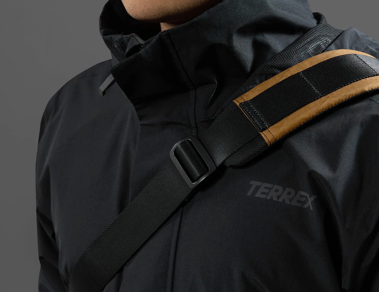 Black jacket with a visible Terrex logo on a gray background