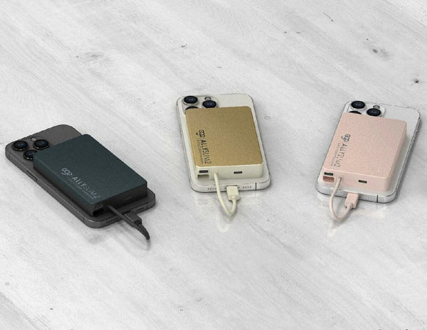 Three portable phone chargers on a light wooden surface