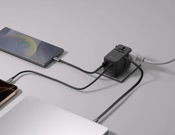 Two electronic devices connected to a power adapter on a gray surface