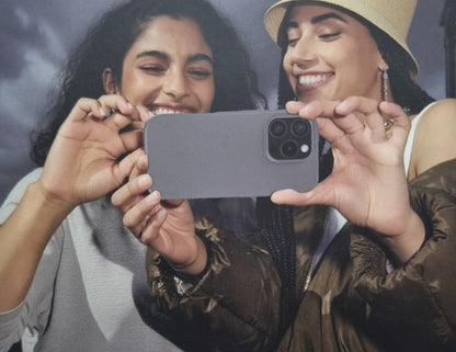 Two women holding a smartphone together, smiling.