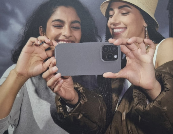 Two women holding a smartphone together, smiling.