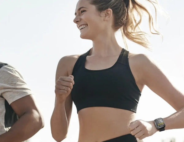 Woman in athletic wear running outdoors with a clear sky background