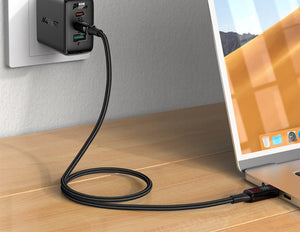 Laptop connected to a power adapter on a wooden surface with a blurred background
