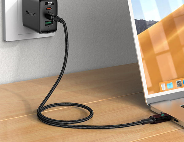Laptop connected to a power adapter on a wooden surface with a blurred background