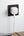White smart plug on a black wall socket with a white cable, against a light gray wall.