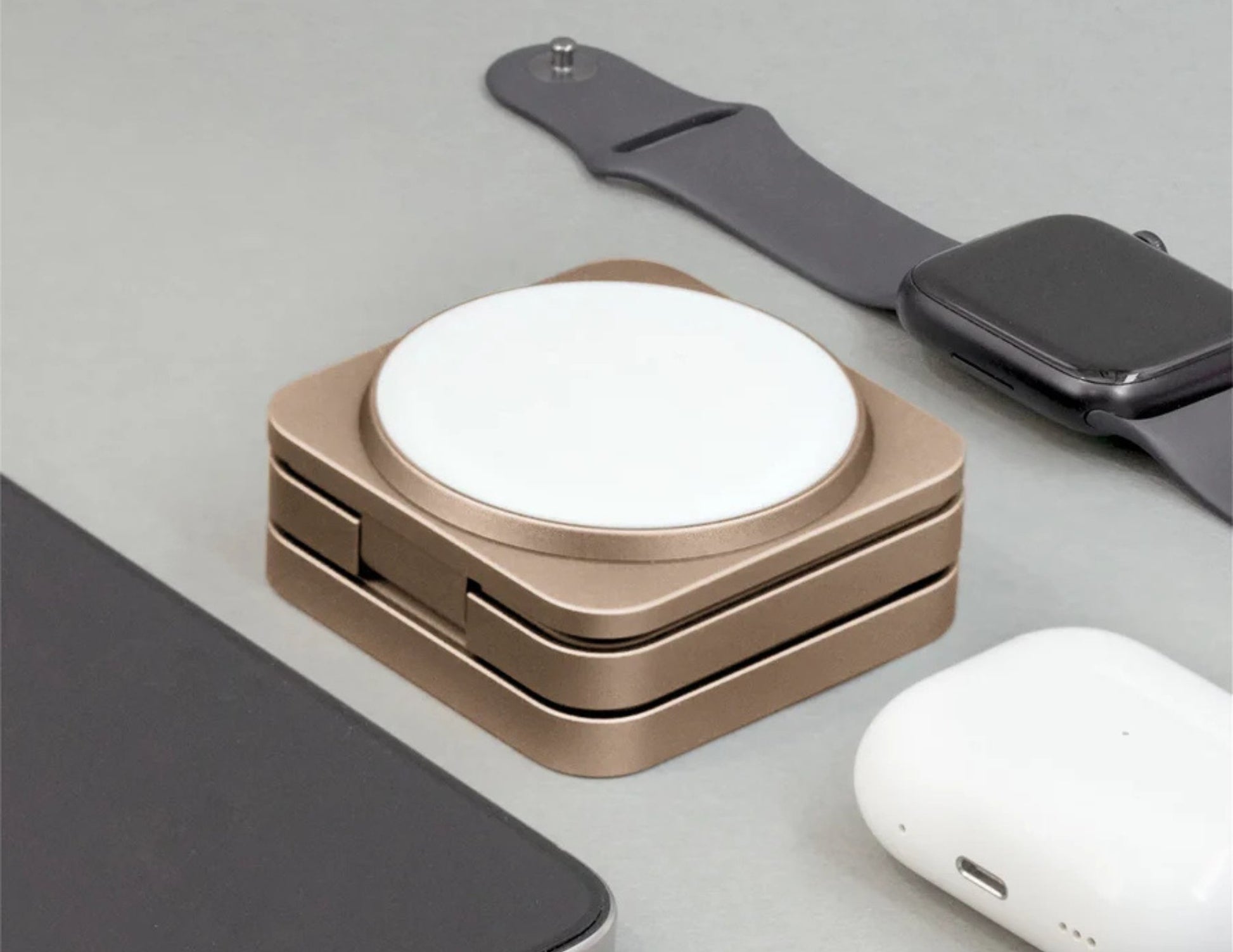 Wireless charging pad with Apple Watch and AirPods on a light gray surface