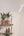 Two wooden shelves with potted plants and decorative items against a white wall.