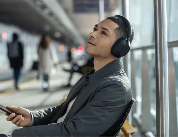 Man wearing headphones and looking out a window in a train station