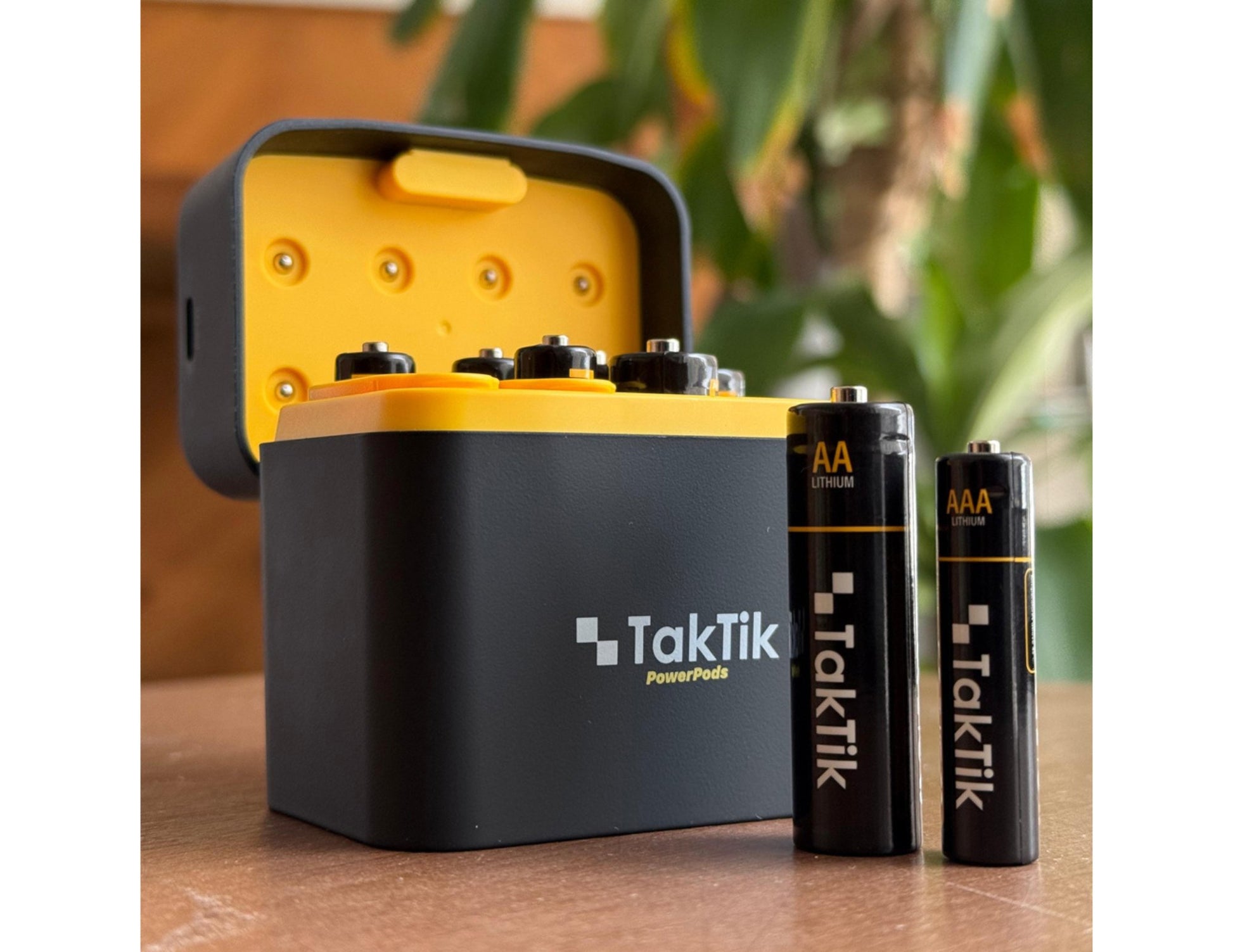 TakTik battery charger with batteries on a wooden surface