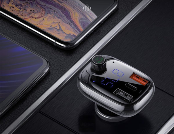 Car charger with Bluetooth speaker on a dark surface with two smartphones.