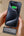 Person holding a smartphone with a charging case on a beige surface