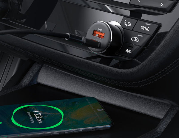 Car dashboard with a smartphone on a wireless charger and car controls.