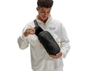 Person wearing a white hoodie with text holding a Tomtoc GameOn-G49 Nintendo Switch 2 Sling Bag – Black (G49S1D1) on a white background