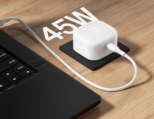 White power adapter with cable on a wooden surface next to a laptop, with '45W' text above.