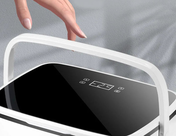 Hand holding a white electronic device with a black screen and control buttons on a gray background