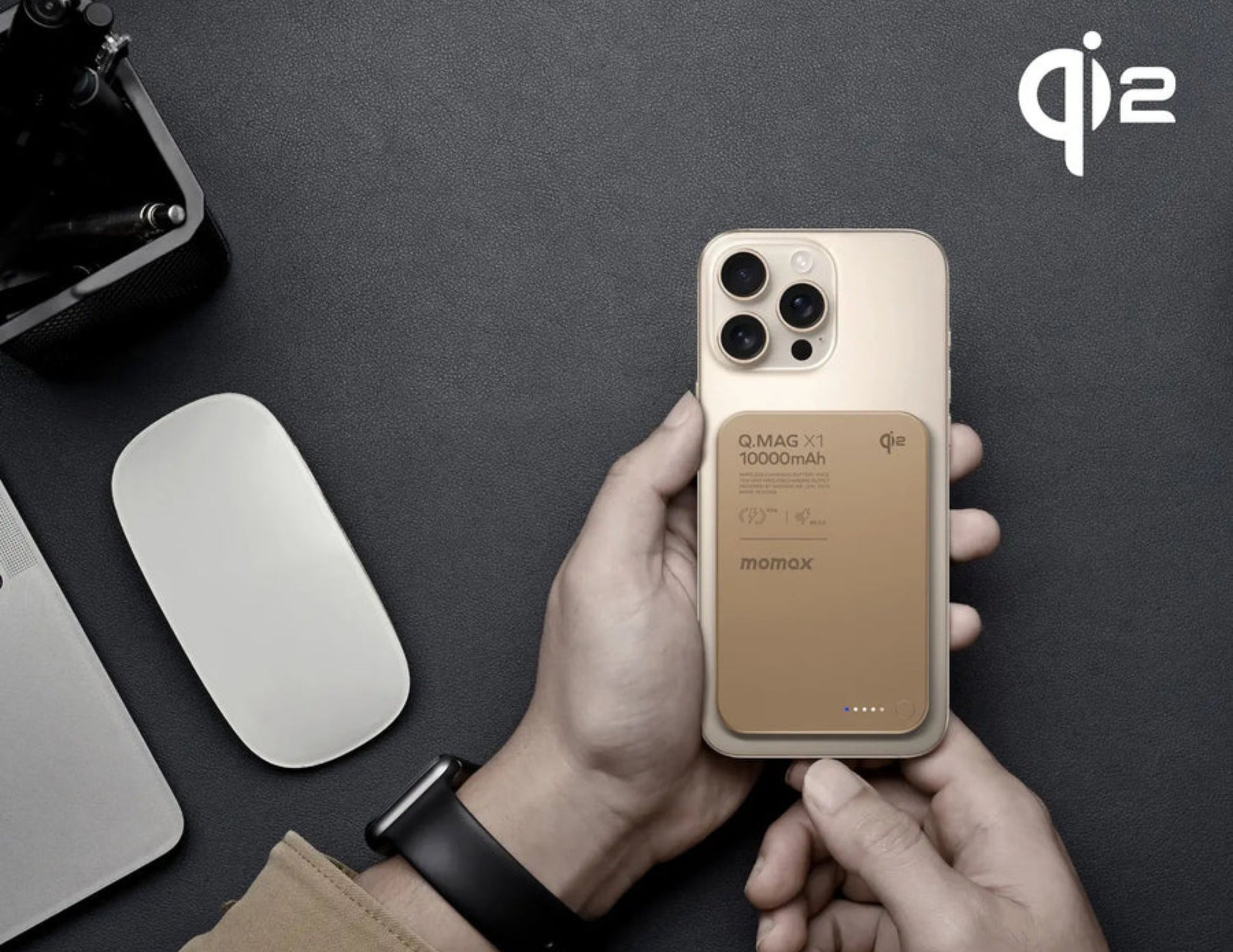 Person holding a phone with a brown case, QI2 logo visible, on a dark surface.