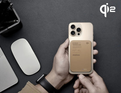 Person holding a phone with a brown case, QI2 logo visible, on a dark surface.