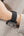 Smartwatch with black band on person's wrist wearing beige sweater