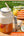 Juice cup with straw and lid on a wooden surface, surrounded by fruits and text about features.