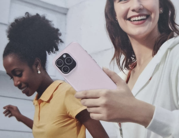 Two women holding a pink smartphone with a white background