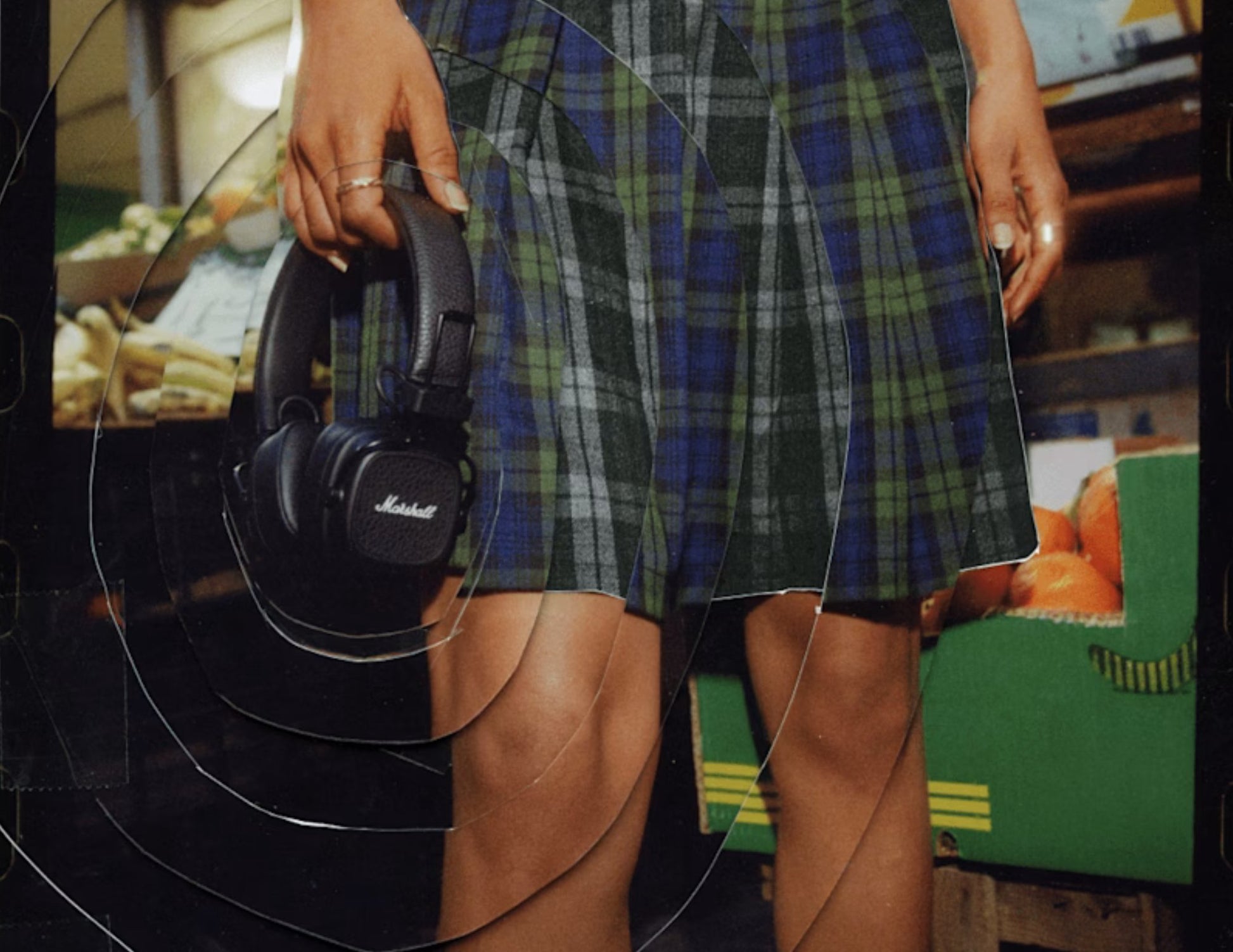 Person holding Marshall headphones with a blurred indoor setting