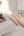 Hand holding a white remote control in a bedroom setting with a bed and stuffed animals.