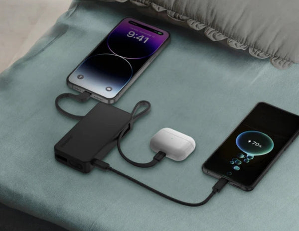 Two smartphones connected to a power bank on a light blue fabric surface.