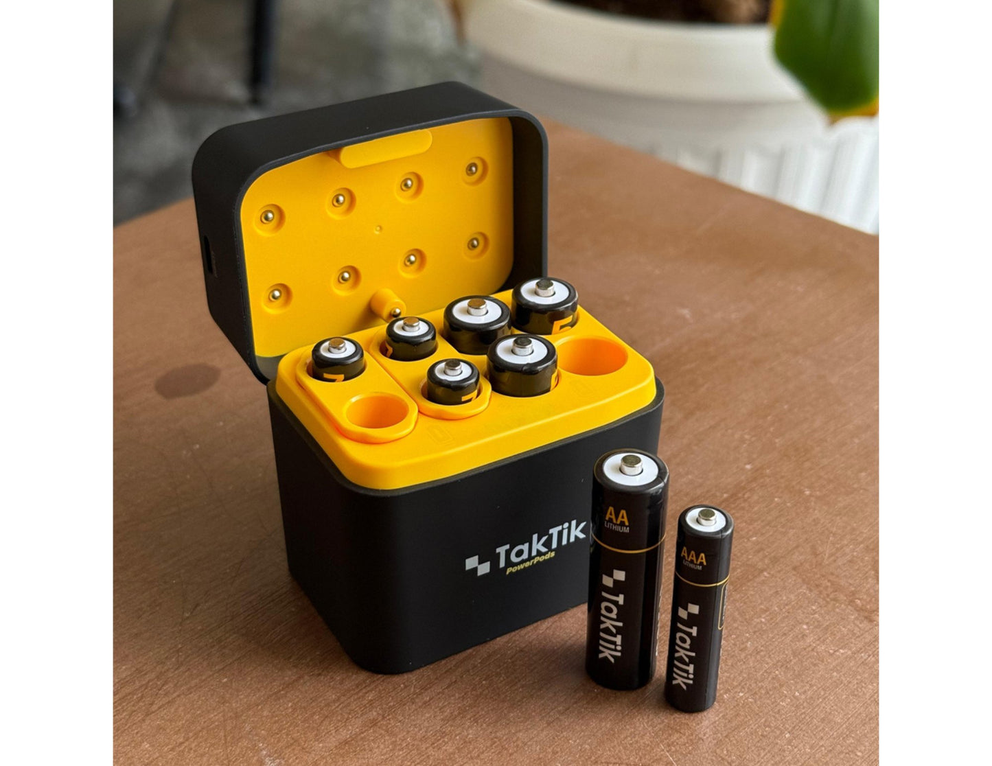 TakTik battery charger with batteries on a wooden surface
