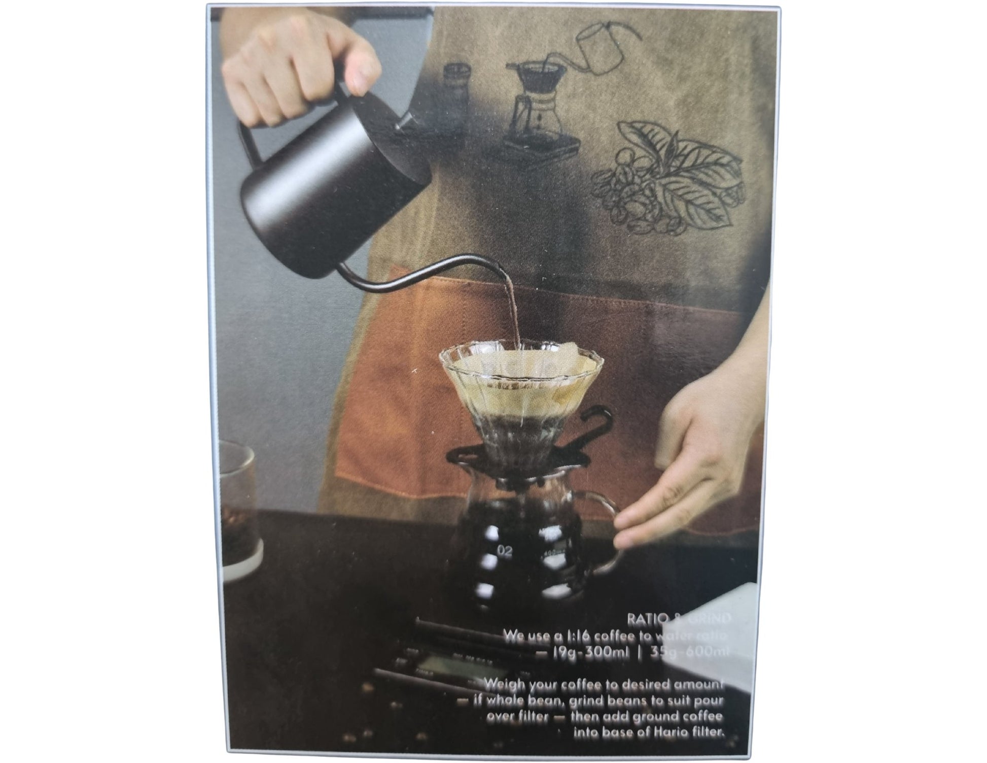 Person making coffee using a pour-over method with a coffee maker and kettle.