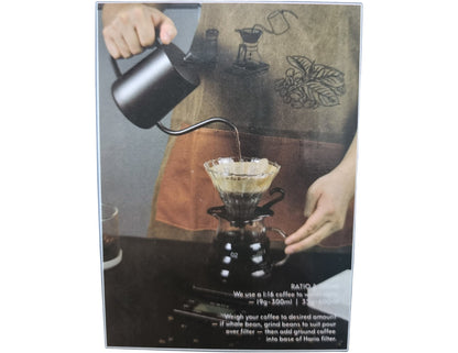 Person making coffee using a pour-over method with a coffee maker and kettle.