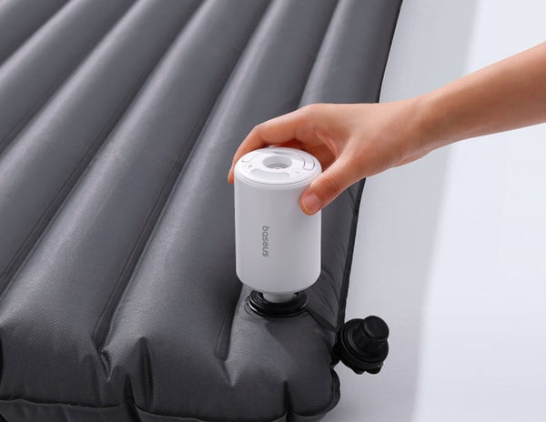 Hand holding a white pump attached to an inflatable mattress
